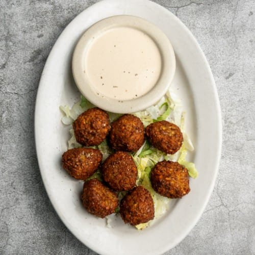 Falafel Sandwich Served with Tahini Sauce and French Fries.